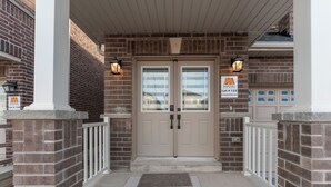 A brick building with a double door entrance, a covered porch, and a mailbox. - 100% Private and Spotless ~Fresh Linens ~New House (Thorold)