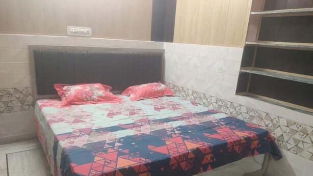 A bedroom with a bed, a headboard, a window, and a tiled wall. - Saraswat Niwas (Udaipur)