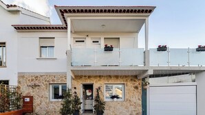Un immeuble de deux étages avec une façade en pierre, un balcon orné de plantes en pot et un garage.