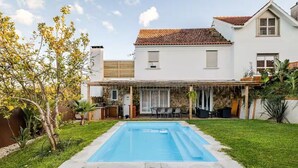 Une maison avec une piscine, un patio couvert et un jardin.