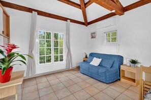 A room with a blue sofa, a wooden table, a potted plant, and a window with curtains.