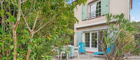 A house with a patio, outdoor furniture, and a potted plant.
