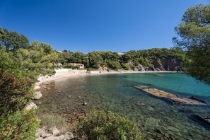 A coastal area with clear water, rocky shore, and a building with a red roof. - Studio Apartment 'Var Hyères  Proche Plage' with Private Terrace, Wi-Fi and Air Conditioning (La Garde)