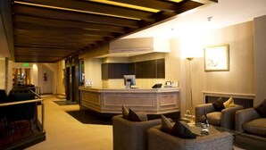 Un vestíbulo de hotel con una recepción, zona de estar y diseño moderno.