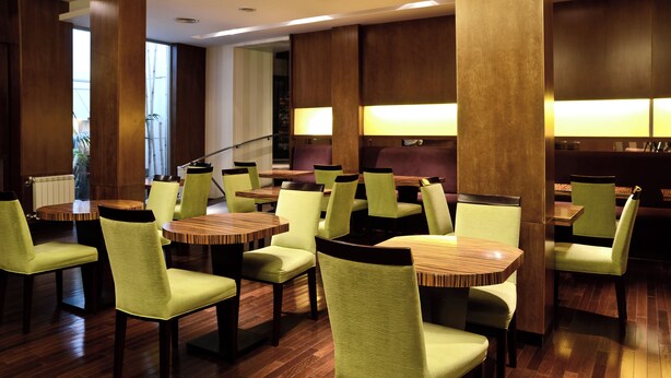 A restaurant with wooden tables and chairs, a staircase, and a view of the outside. - Hotel Presidente (Mar del Plata)