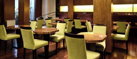 A restaurant with wooden tables and chairs, a staircase, and a view of the outside.