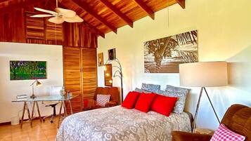 Une chambre à coucher avec un lit, un bureau, une chaise et un ventilateur de plafond.