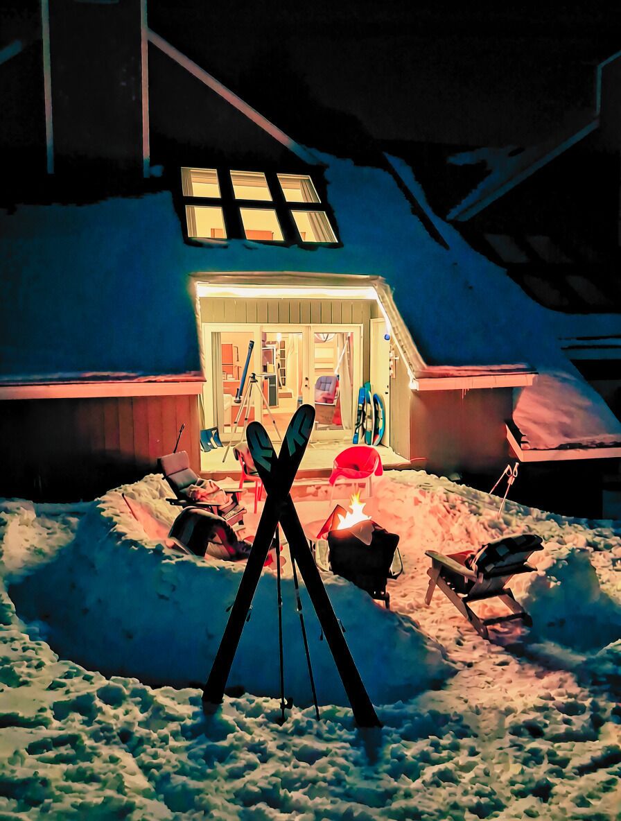 A snow-covered landscape with a building featuring a large window and a ski lift.
