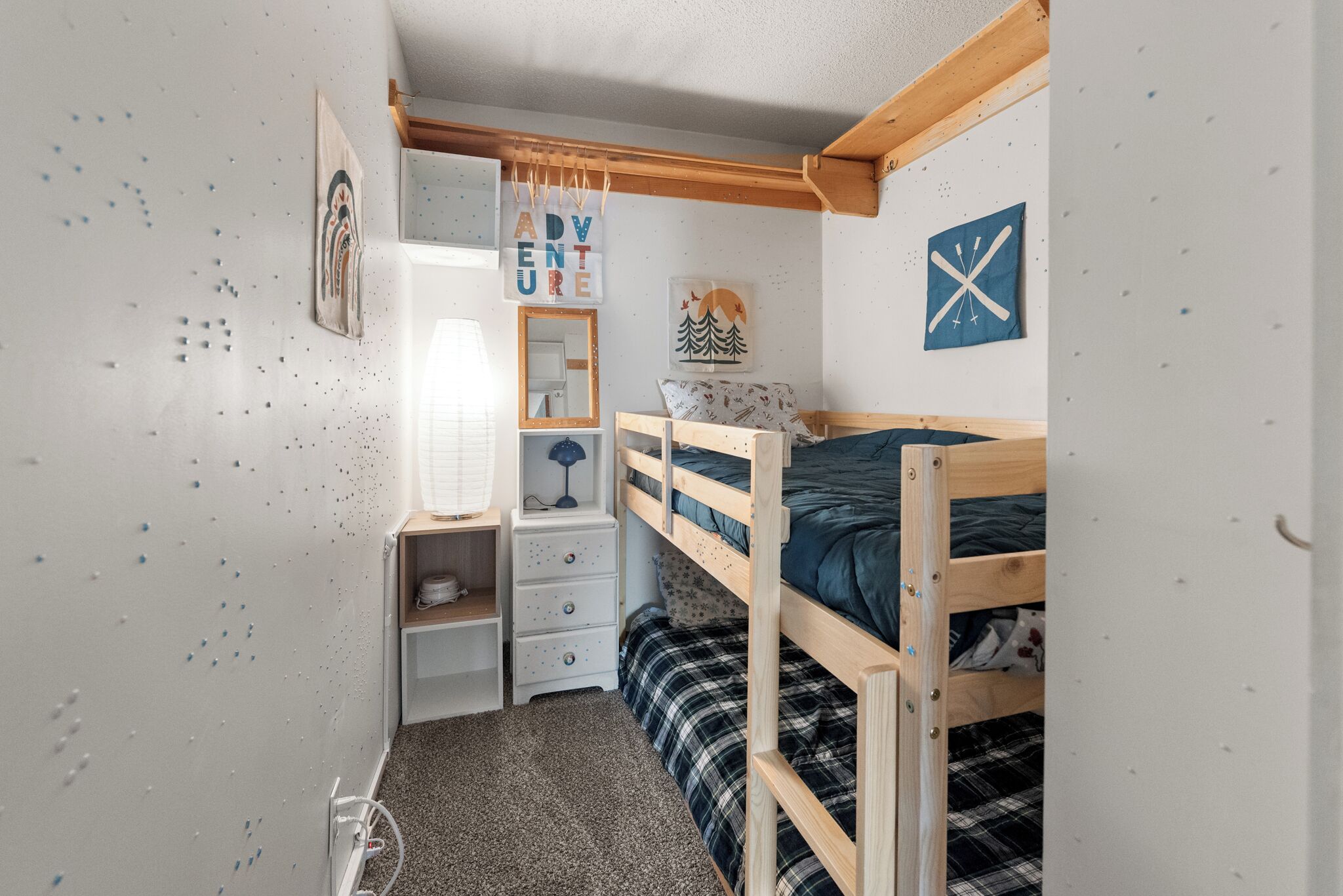 Une chambre d’enfant avec des lits superposés, un bureau, un miroir et des décorations murales.