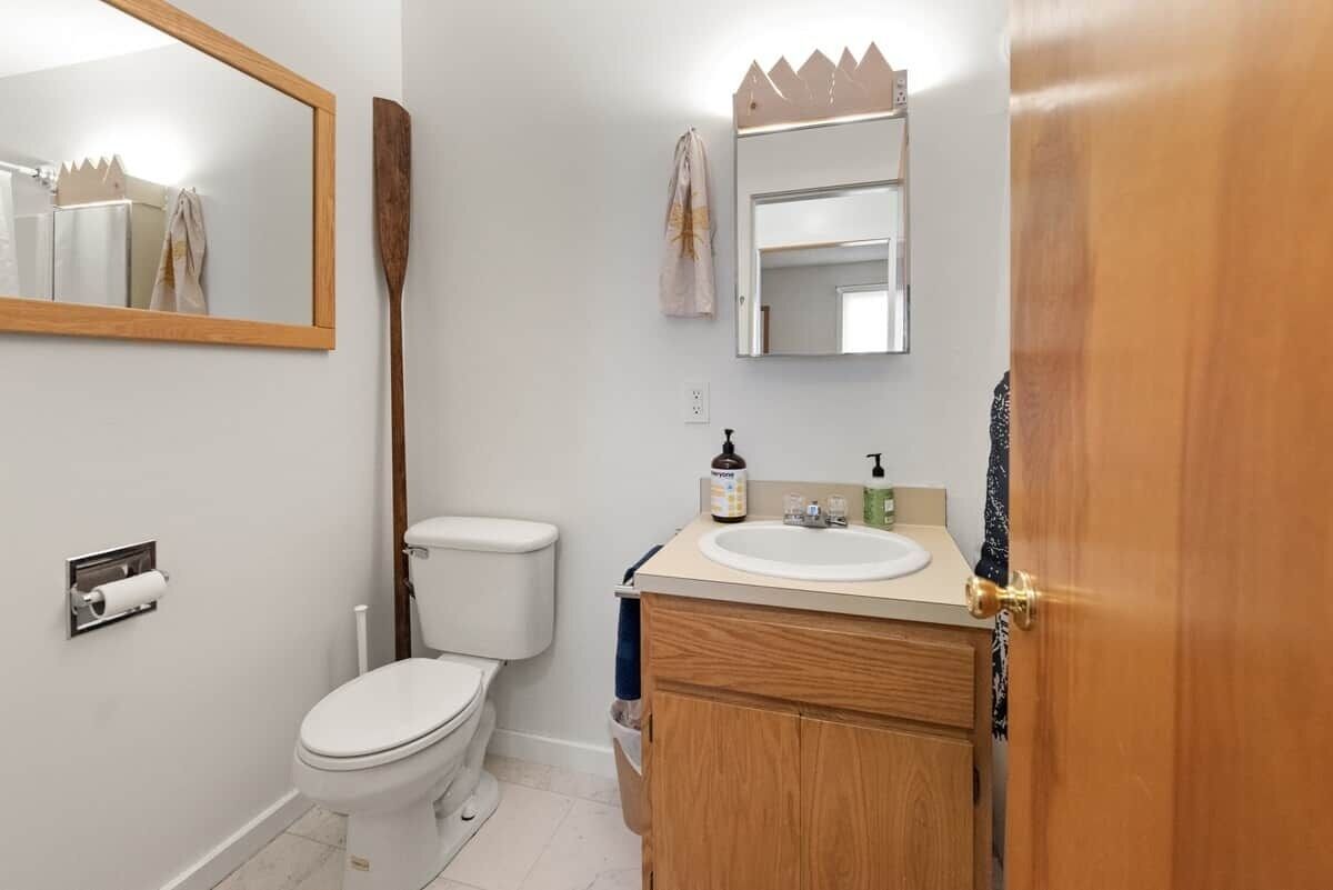 Un bagno con il water, un lavandino, uno specchio e una porta in legno.