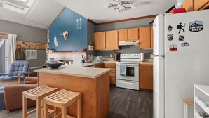Una cocina moderna con armarios de madera, una isla central y un refrigerador decorado con imanes de temática de viajes.