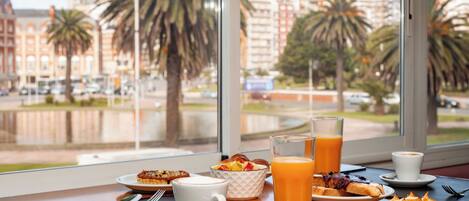 A breakfast table with a cup, a glass of orange juice, and a plate of food.