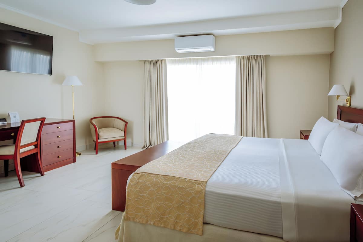 Une chambre d’hôtel avec un lit, un bureau, une chaise et un téléviseur.