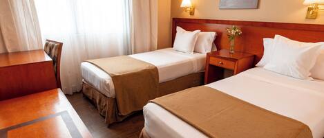 Ein Hotelzimmer mit zwei Betten, einem Schreibtisch und einem Stuhl.