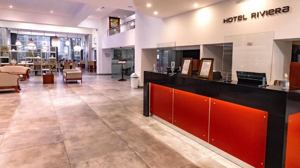Un espace d’accueil d’hôtel au design moderne, comprenant un comptoir d’accueil et un coin salon.