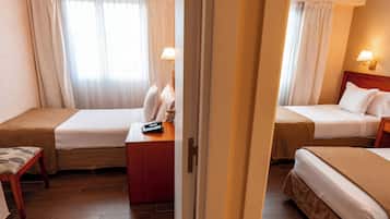 A hotel room with two beds, a desk, a chair, and a window with curtains.