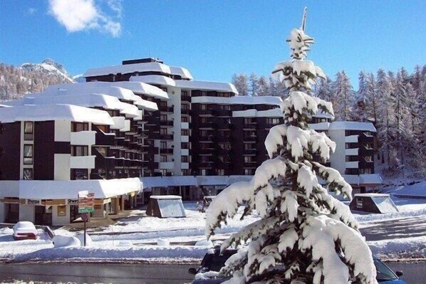 A multi-story hotel with a modern architectural design, featuring balconies and a snow-covered environment. - 10m from resort center, 3rd floor, tv, ski locker, 18m², Vars (Vars)