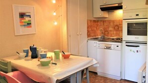 Une petite cuisine équipée d’une table à manger, de chaises, d’une cuisinière, d’un lave-vaisselle et d’un réfrigérateur.