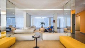 A modern hotel lobby with a central seating area, a small table, and a potted plant. - Studio with Pool and Garage – 7 min from Allianz (São Paulo)