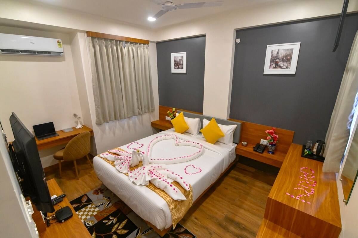 A hotel room with a bed, desk, chair, and a TV.