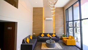 Un moderno vestíbulo con un conjunto de sofás, una mesita de centro y un sillón amarillo.