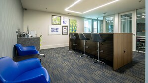 A modern office space with a reception desk, blue chairs, and a wooden counter. - The George, 3BR Home by Velvet Ditch Villas (Oxford)