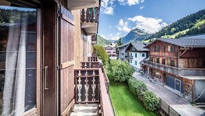 A wooden balcony with a view of a mountain and traditional buildings.