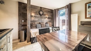 A modern kitchen with a wooden accent wall, a dining table, and a built-in bench with cushions.