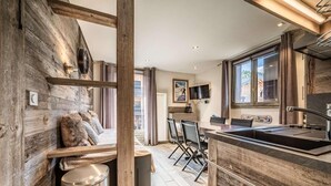 A modern kitchen with wooden accents, a dining area with chairs, and a large window providing natural light.