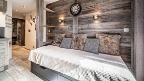 A bedroom with a wooden headboard, a bed with a white blanket, and a wall clock.
