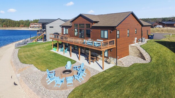 A two-story house with a deck overlooking a lake, a fire pit, and outdoor seating. - Lake House for 14! Fire Pit + Game Room (New Lisbon)