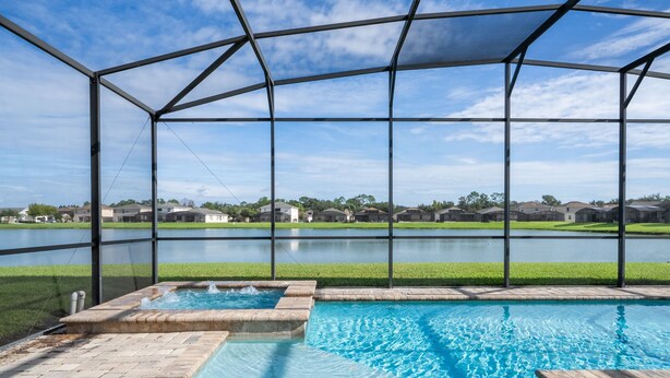 Una piscina con vistas a un lago y casas al fondo.