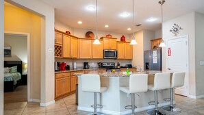 Una cocina moderna con armarios de madera, una isla central con taburetes de bar, electrodomésticos de acero inoxidable e iluminación colgante.