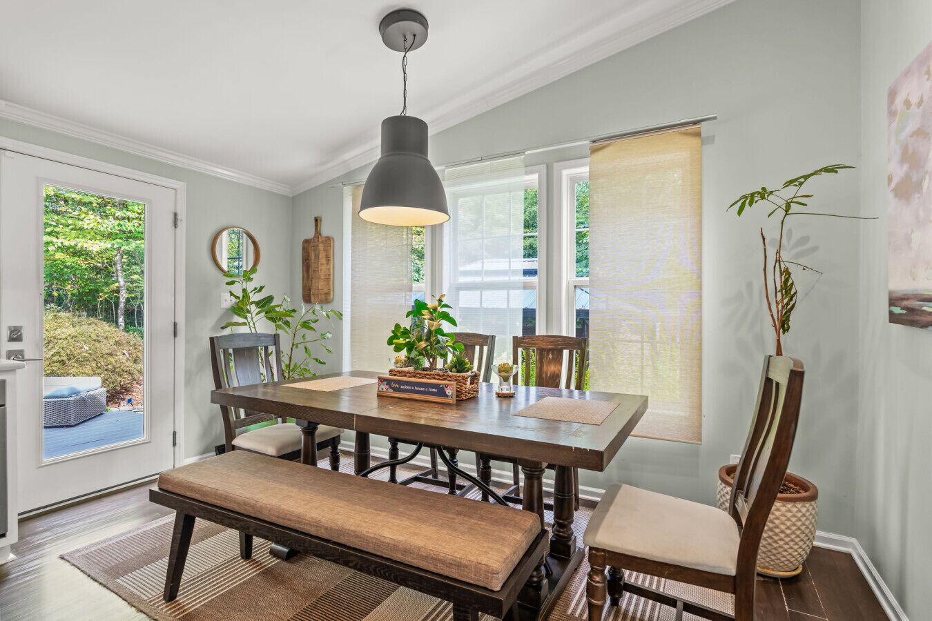 Un espace repas avec une table en bois foncé, des bancs rembourrés et une suspension décorative.