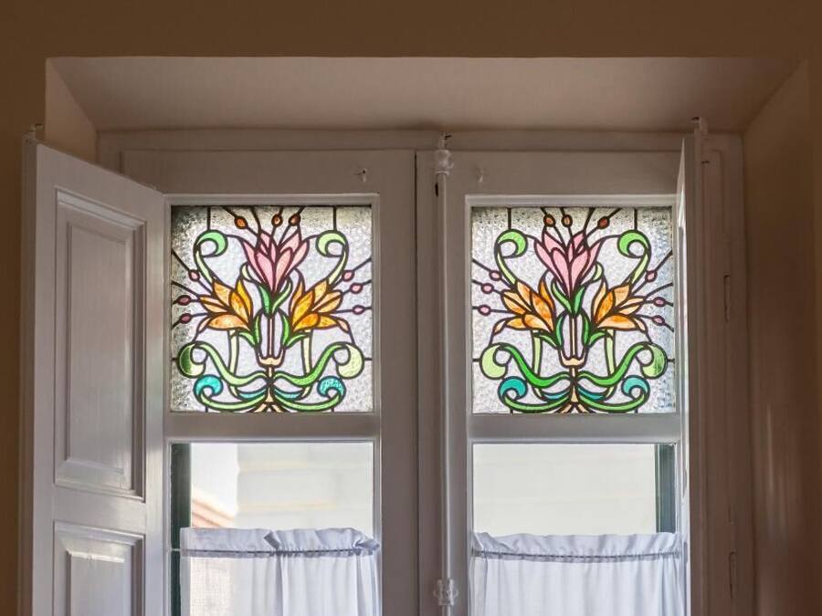 Una habitación con dos ventanas decoradas con vidrieras.