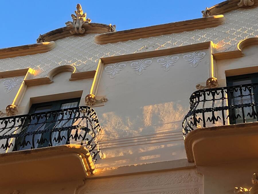 Fachada de edificio con detalles arquitectónicos ornamentales, incluyendo molduras decorativas y un techo con diseños.