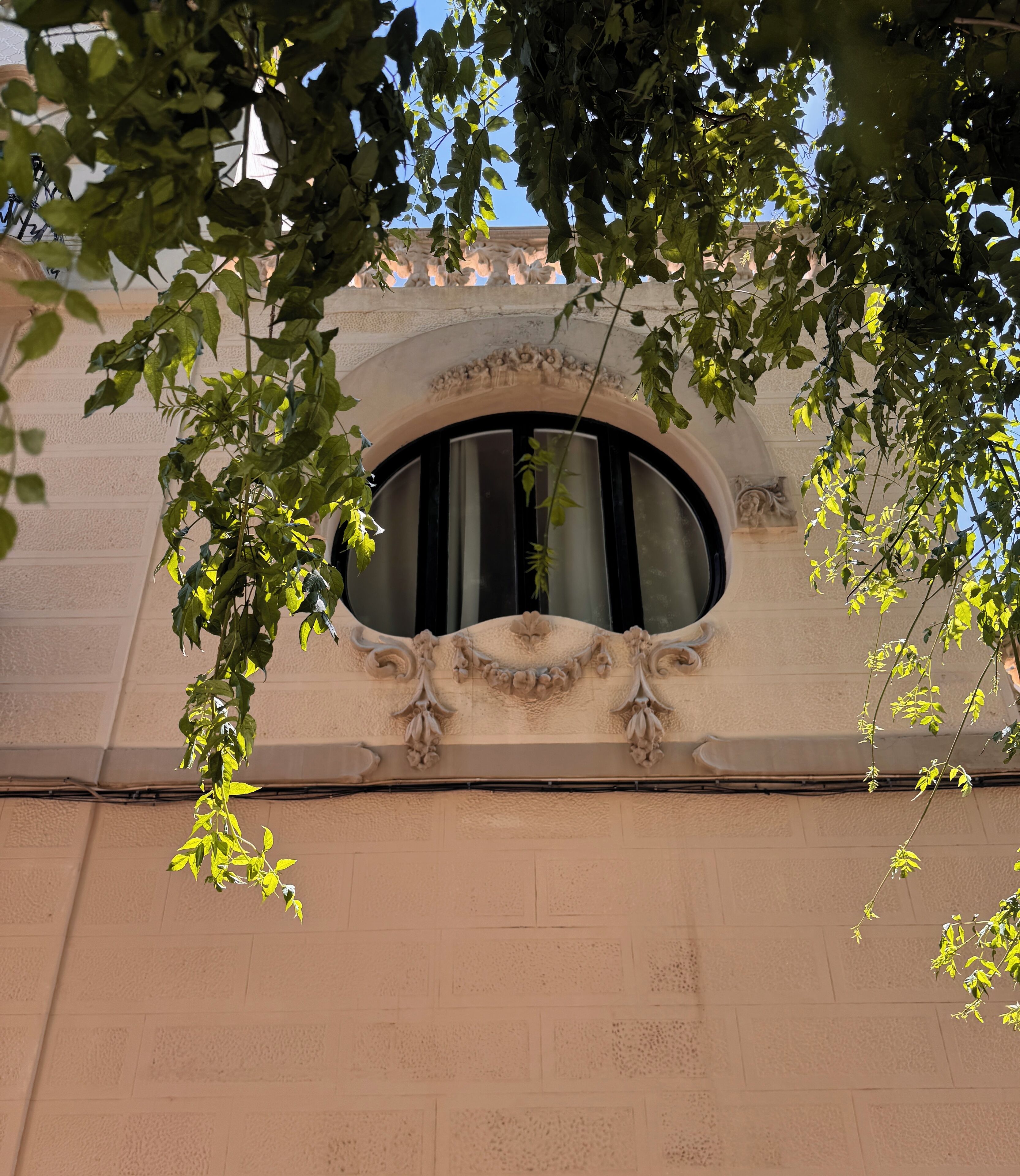 A building facade with a large arched window framed by ornate stone carvings.