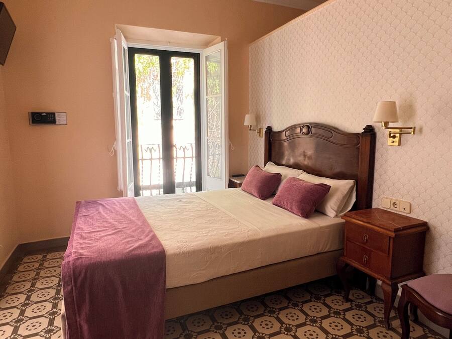 Quarto com cama, mesas de cabeceira, rodapé e piso estampado.