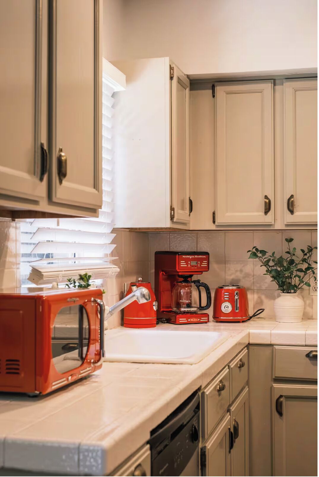 A kitchen with white cabinets, a red coffee maker, a toaster, and a microwave.