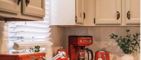 A kitchen with white cabinets, a red coffee maker, a toaster, and a microwave.