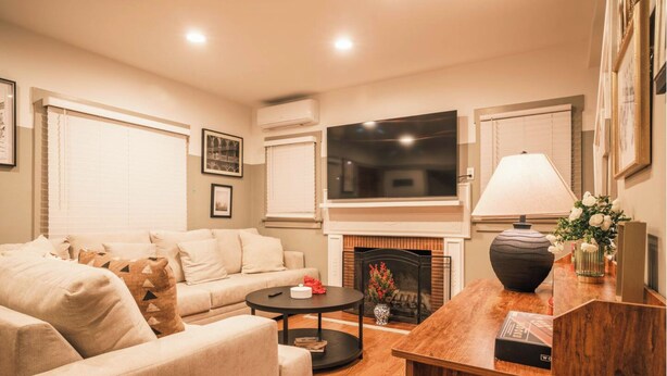 Una sala de estar con sofá, mesa de centro, chimenea, televisor y elementos decorativos.