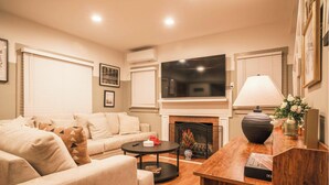 Una sala de estar con sofá, mesa de centro, chimenea, televisor y elementos decorativos.