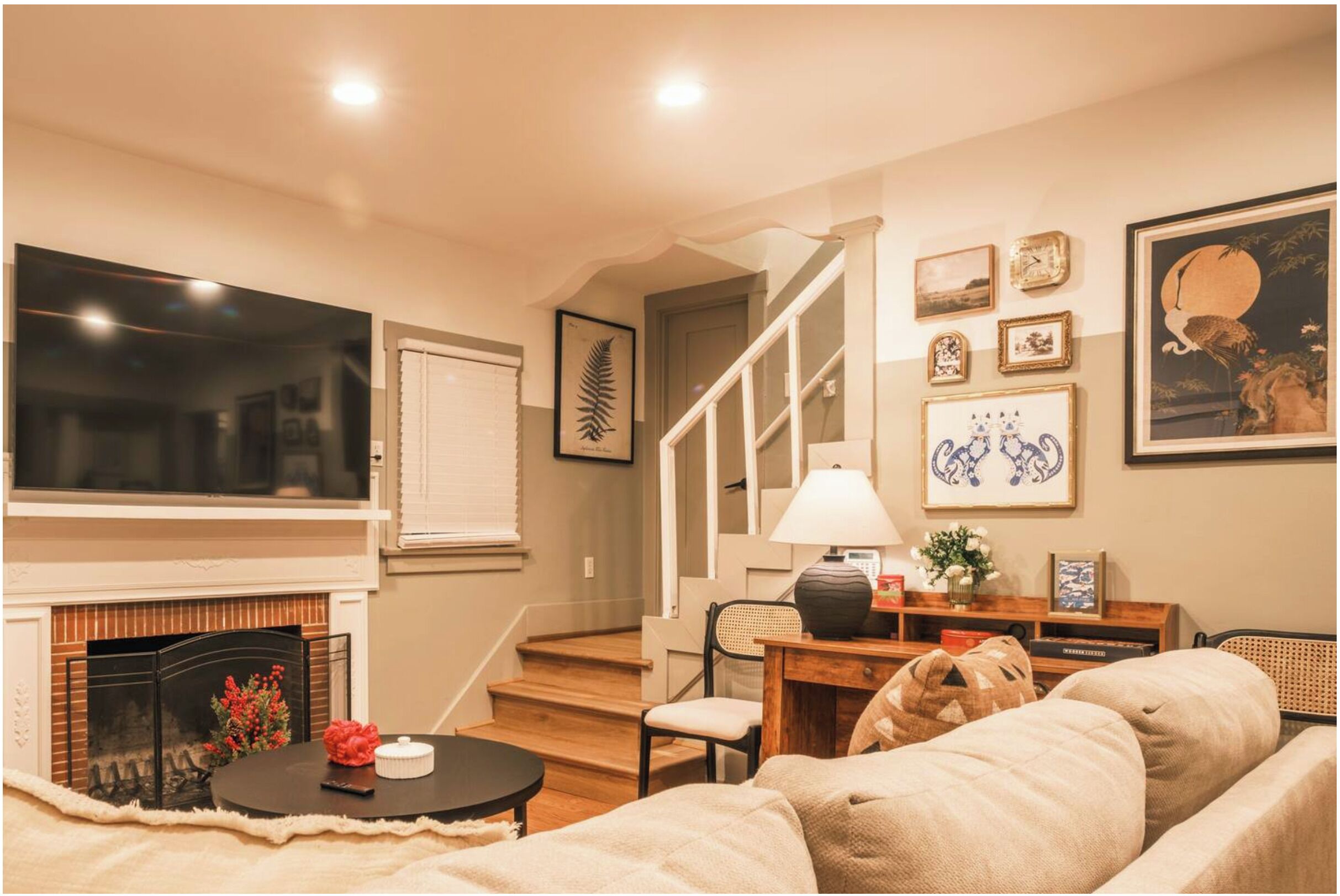 A living room with a fireplace, a sofa, a coffee table, and a staircase leading to another level.