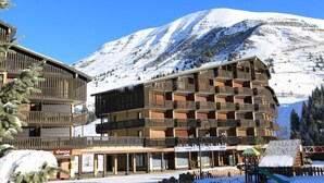 A multi-story hotel with balconies, a ski slope in the background, and a 'Sherpa' sign indicating a nearby shop. - Ski-in/ski-out & foot of the slopes, 2nd floor, balcony, tv, 17m², Auris en Oisans (Auris)