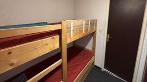 A bunk bed with red bedding in a room with a door and white walls. - Ski-in/ski-out & foot of the slopes, 2nd floor, balcony, tv, 17m², Auris en Oisans (Auris)