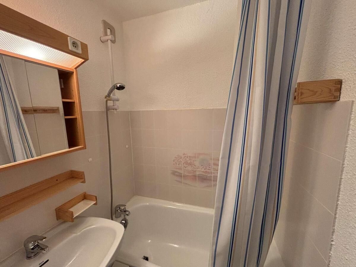 A bathroom with a bathtub, a sink, a mirror, and a shower curtain.
