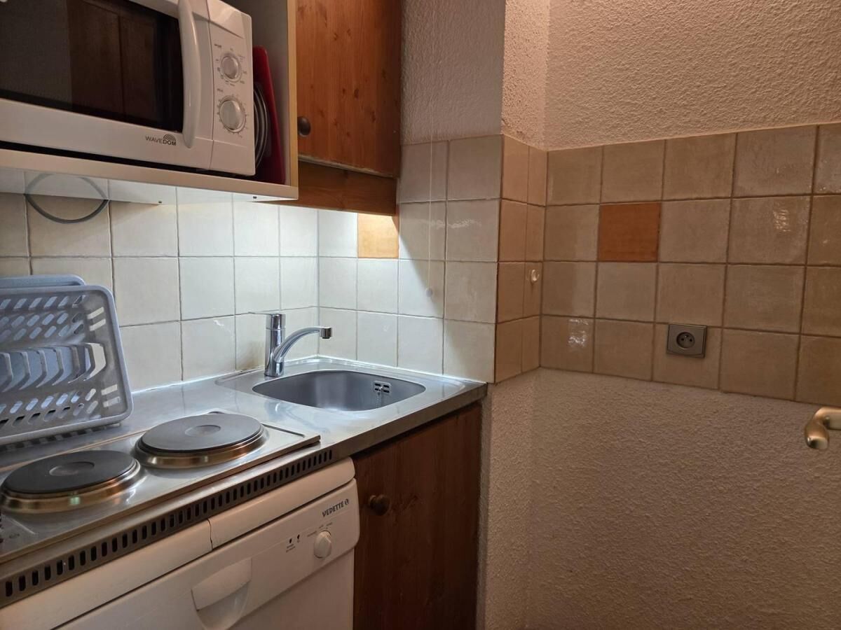 Eine kleine Küche mit Mikrowelle, Herd, Spüle und Holzschränken.
