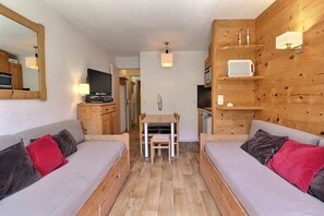A compact living space with two sofas, a dining table, and a kitchen area. - 10m from ski slopes, 7th floor, ski locker, 23m², Méribel-Mottaret (Méribel - Les Allues)