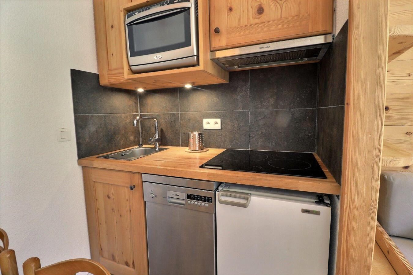 A compact kitchen with a built-in oven, a dishwasher, and a stovetop.