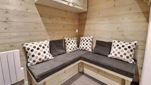 Ein Ecksofa mit Polka-Dot-Kissen, eine Holzbalkendecke und ein weißer Heizkörper.